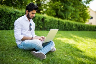 Man sits on the grass using his laptop